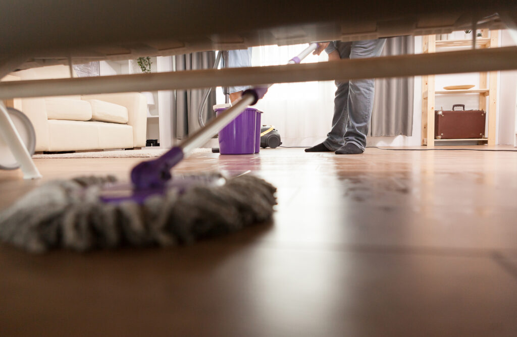 cleaning under bed with a mop