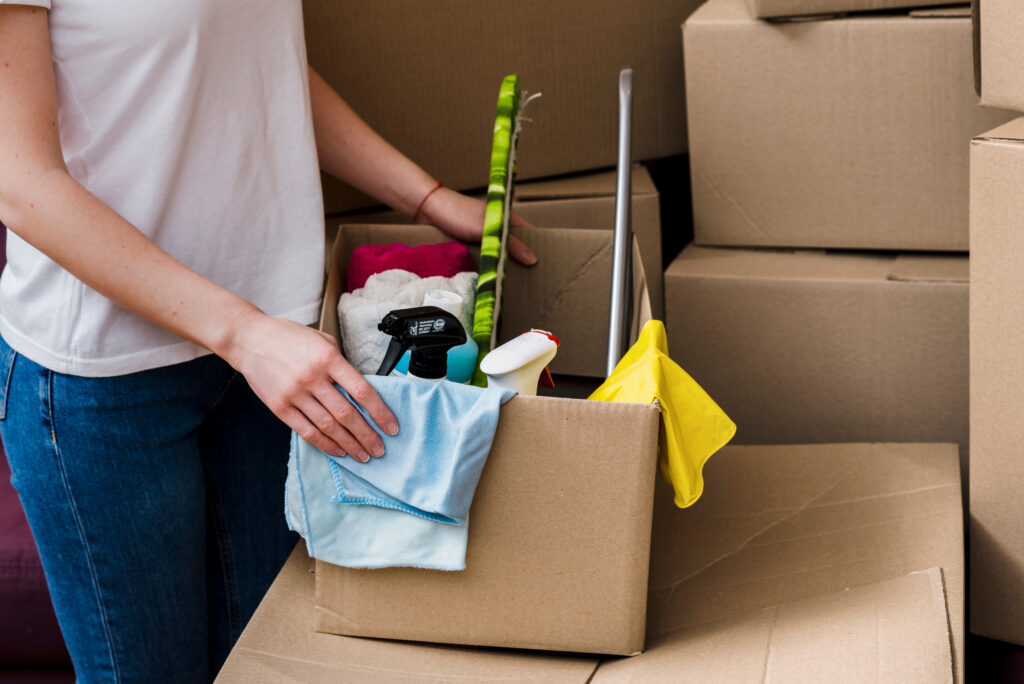 woman holding box full of cleaning supplies